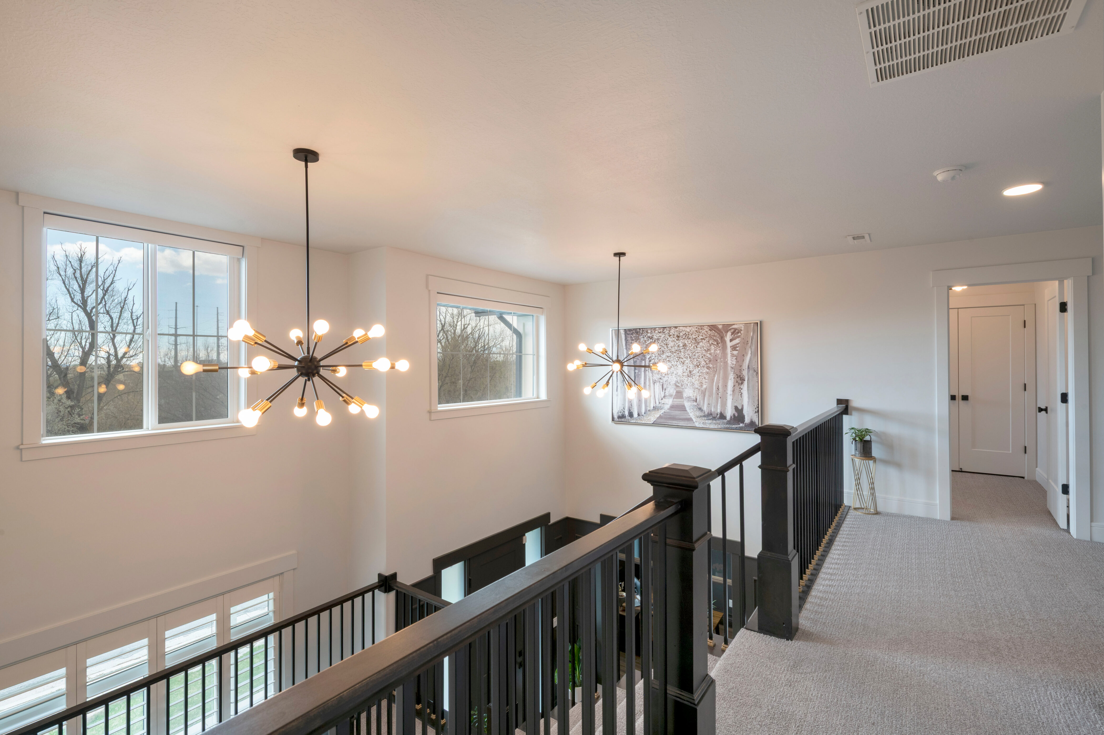 Hall with an upstairs landing, carpet flooring, baseboards, visible vents, and an inviting chandelier