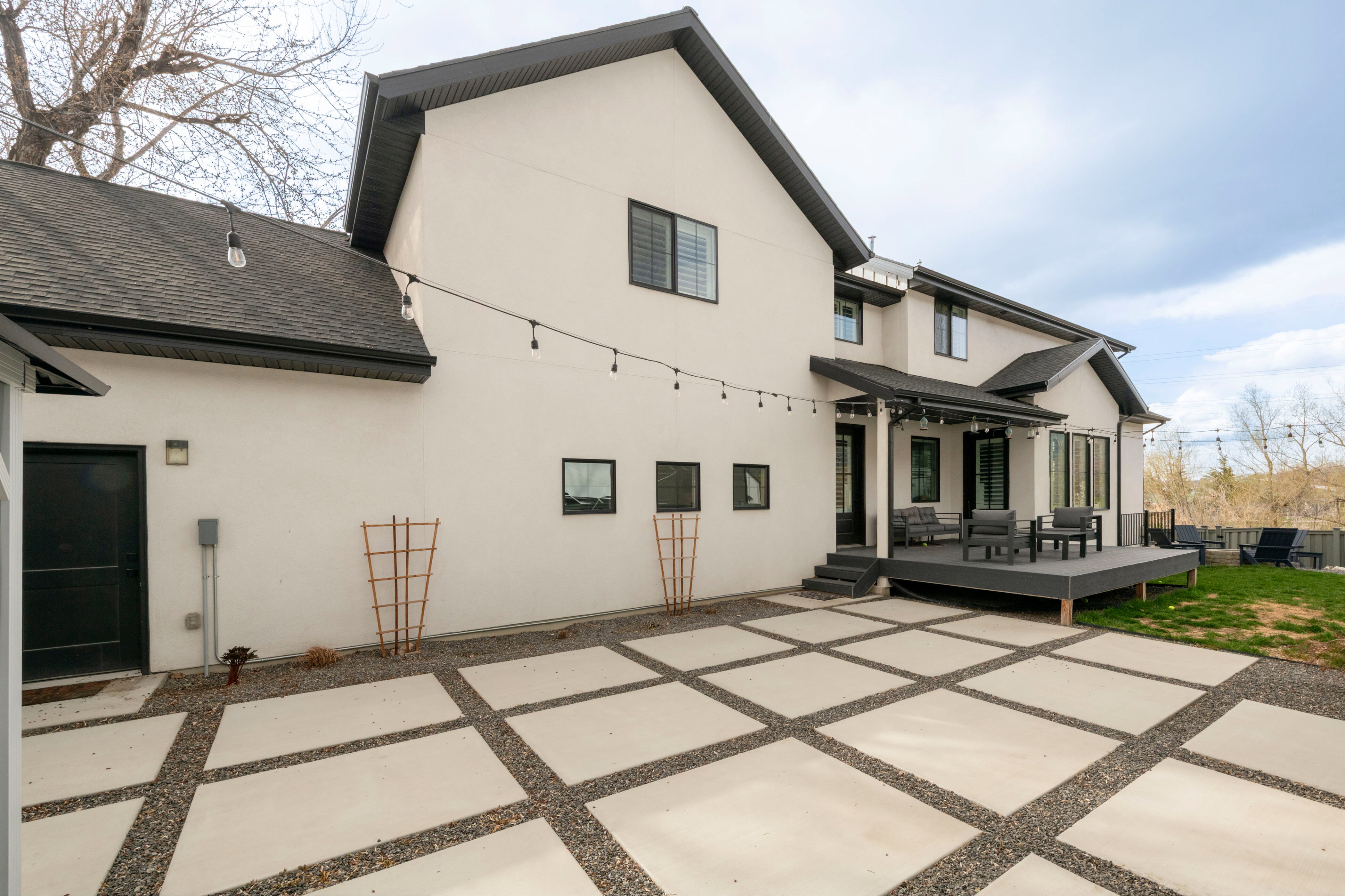 Rear view of house featuring stucco siding, a deck, a patio, and roof with shingles
