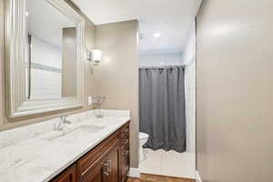 Full bath with toilet, vanity, baseboards, and a shower with curtain