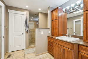 Full bathroom featuring baseboards, tiled shower, and vanity