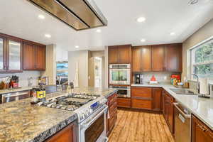 Kitchen featuring glass insert cabinets, a sink, light wood finished floors, recessed lighting, and stainless steel appliances