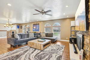 Living area featuring ceiling fan with notable chandelier, a textured ceiling, recessed lighting, wood finished floors, and baseboards