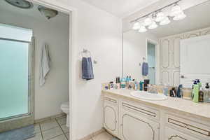 Bathroom with tile patterned floors, vanity, walk in shower, and toilet