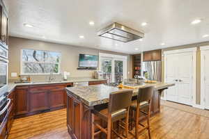 Kitchen with a center island, a sink, appliances with stainless steel finishes, a kitchen breakfast bar, and light wood-style floors