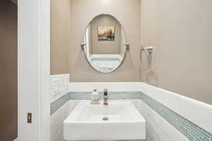 Bathroom with a sink, wainscoting, and tile walls