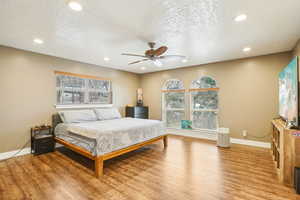 Bedroom featuring light wood-style floors, ceiling fan, a textured ceiling, recessed lighting, and baseboards