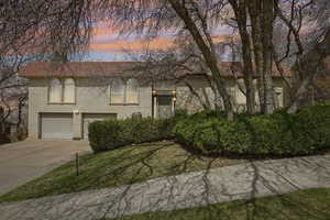 Bi-level home with driveway, a garage, a front lawn, and brick siding