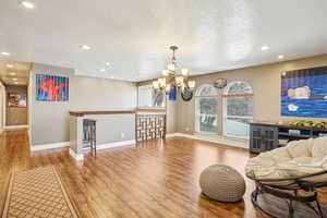 Living area featuring a textured ceiling, recessed lighting, a chandelier, wood finished floors, and baseboards