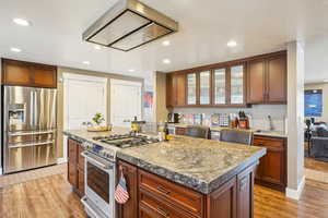 Kitchen featuring light wood-style flooring, appliances with stainless steel finishes, a sink, and glass insert cabinets