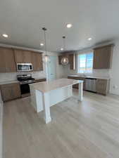 Kitchen featuring stainless steel appliances, backsplash, a kitchen island, Pendant lights, light wood-style floors, and recessed lighting