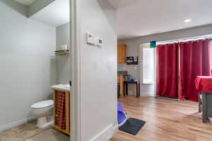 Bathroom with toilet, recessed lighting, baseboards, and wood finished floors