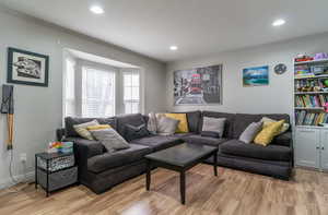 Living area featuring light wood-style flooring, crown molding, and recessed lighting