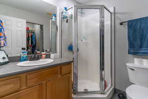 The primary bathroom features a shower, toilet and vanity with sink and large mirror, and opens to the walk-in closet.