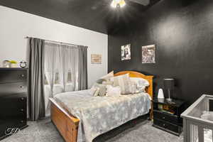Carpeted bedroom featuring vaulted ceiling and ceiling fan