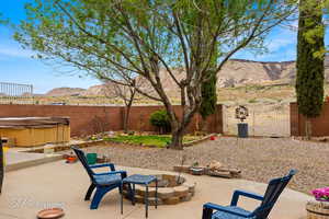 View of patio / terrace with a fenced backyard, a fire pit, a mountain view, and a hot tub