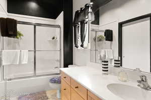 Full bathroom featuring toilet, vanity, and bath / shower combo with glass door