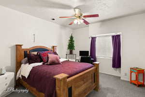 Bedroom featuring a textured wall, baseboards, a textured ceiling, carpet floors, and ceiling fan