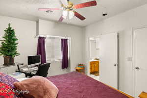 Bedroom featuring a textured wall, a textured ceiling, visible vents, and ceiling fan