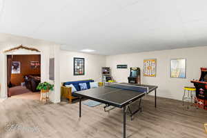 Recreation room featuring baseboards, wood finished floors, and a drop ceiling