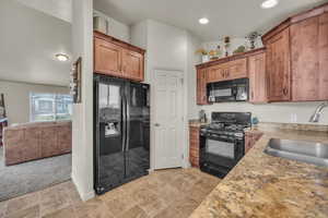 Kitchen with light countertops, recessed lighting, a sink, black appliances, and brown cabinets