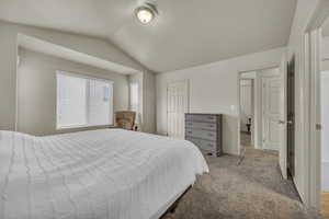 Bedroom with light colored carpet, lofted ceiling, and baseboards