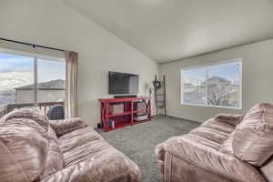 Carpeted living room featuring plenty of natural light, baseboards, and vaulted ceiling