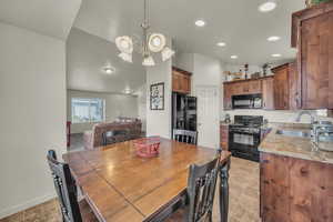 Dining room with baseboards, lofted ceiling, a chandelier, and recessed lighting