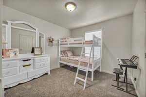Bedroom featuring baseboards, carpet flooring, and a textured ceiling