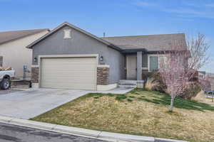Ranch-style home with stucco siding, an attached garage, stone siding, and concrete driveway