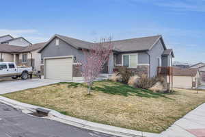 Ranch-style home featuring stone siding, a garage, concrete driveway, and stucco siding