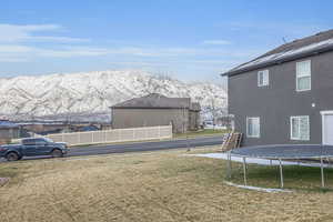View of yard featuring a mountain view, a trampoline, and fence