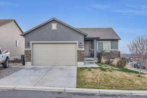 View of front of property featuring stone siding, concrete driveway, stucco siding, and an attached garage