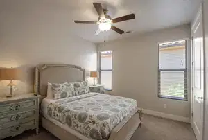 Carpeted bedroom with baseboards, visible vents, and ceiling fan