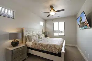 Carpeted bedroom with baseboards, visible vents, and a ceiling fan