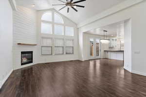 Unfurnished living room with a healthy amount of sunlight, a fireplace, dark wood-type flooring, and a ceiling fan