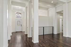 Entryway featuring baseboards, dark wood-style floors, an inviting chandelier, and crown molding