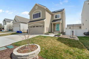 Traditional home featuring fence, an attached garage, concrete driveway, solar panels, and stucco siding