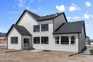 Back of house with stucco siding, roof with shingles, and entry steps