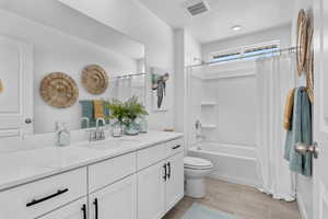 Bathroom with visible vents, toilet, shower / tub combo, and vanity