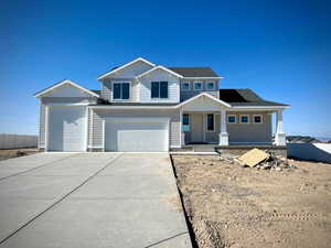 View of front facade with a garage, fence, covered porch, a shingled roof, and driveway