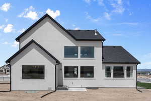 Back of house with stucco siding and roof with shingles