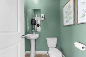 Bathroom featuring toilet, baseboards, and wood finished floors
