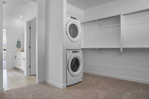 Washroom with baseboards, visible vents, stacked washer / dryer, light carpet, and laundry area
