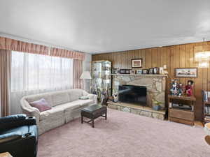 Living room featuring carpet flooring, a fireplace, wood walls, and a chandelier