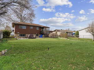 Back of property with a yard and fence