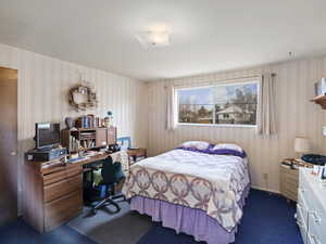 Bedroom featuring wallpapered walls and dark colored carpet