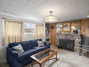 Carpeted living area featuring a fireplace and wooden walls