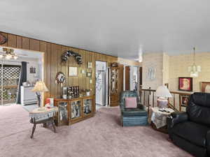 Living area featuring wallpapered walls, carpet floors, baseboard heating, and ceiling fan