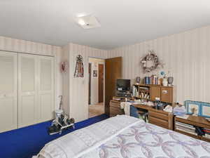 Bedroom with wallpapered walls and a closet