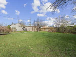 View of yard featuring an outbuilding and fence